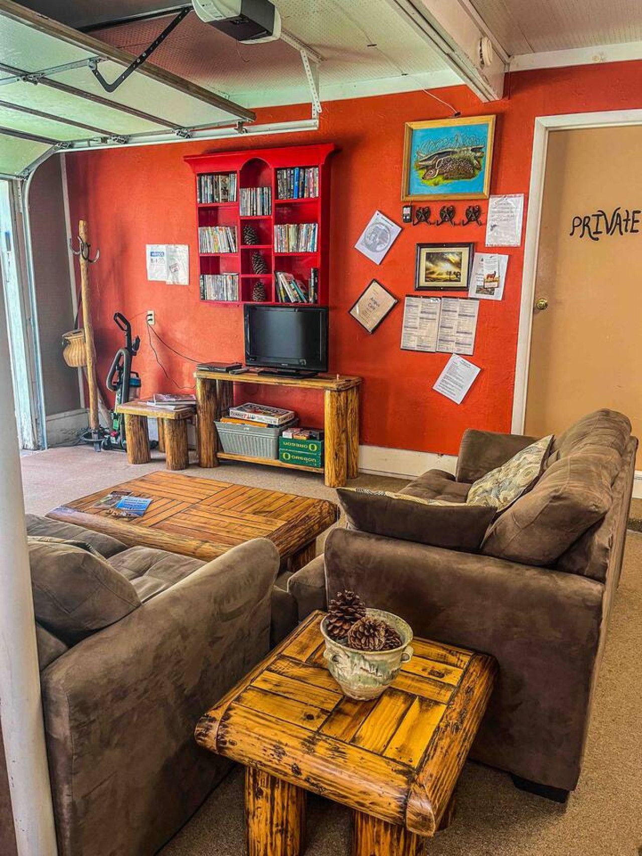 Ett mysigt vardagsrum med en röd vägg, en bokhylla, en tv och en dörr med skylten "PRIVAT".