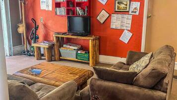 Ett mysigt vardagsrum med en röd vägg, en bokhylla, en tv och en dörr med skylten "PRIVAT".