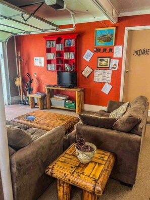 A cozy living room with a red wall, a bookshelf, a television, and a door labeled "PRIVATE".