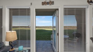 Una habitación con vista a un jardín césped a través de una puerta corrediza de vidrio.