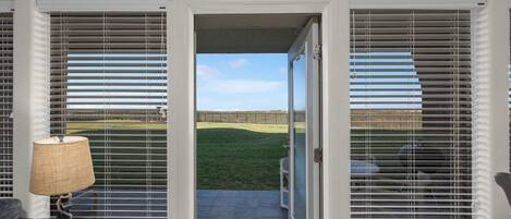 Una habitación con vista a un jardín césped a través de una puerta corrediza de vidrio.
