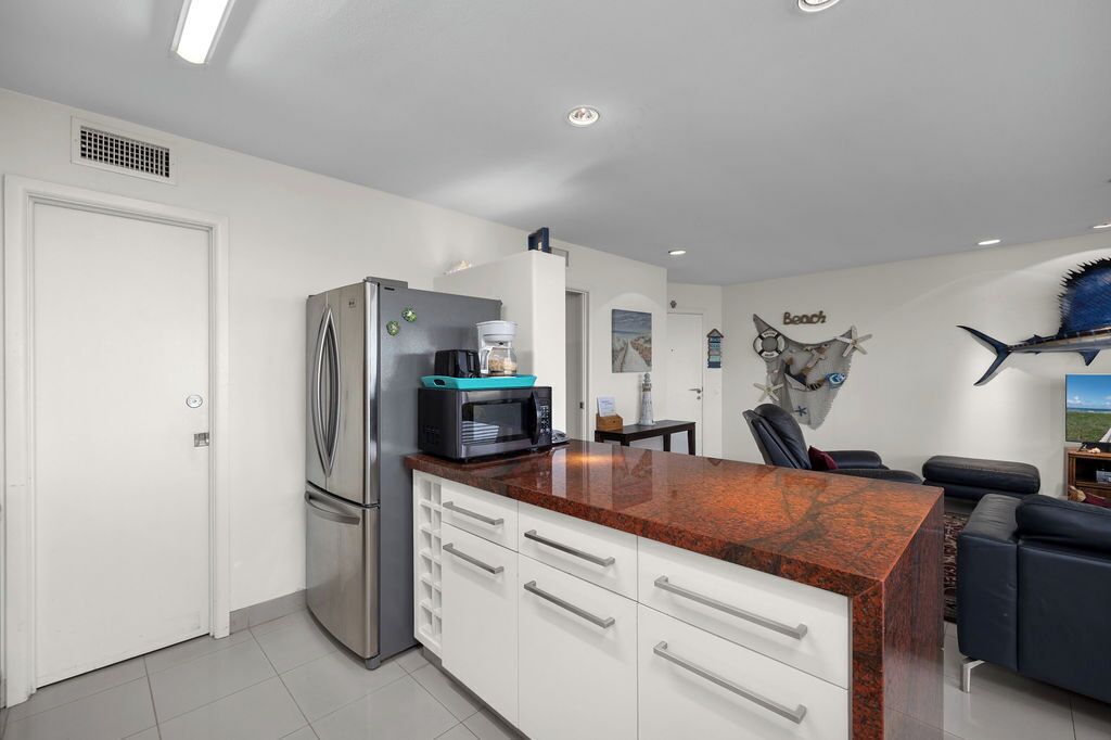 A modern kitchen with white cabinets, a granite countertop, and a built-in microwave.