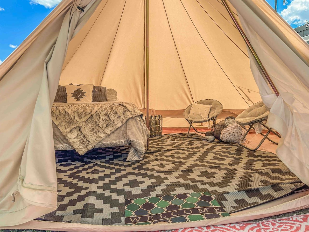 Una carpa con una cama, una silla y una alfombra estampada.