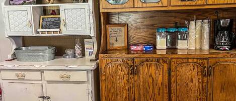 Una cocina de estilo vintage con gabinetes de madera, muebles blancos y diversos utensilios de cocina.