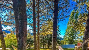 A hammock between trees in a grassy area with a clear blue sky. - The willow boho tent (Irwin)