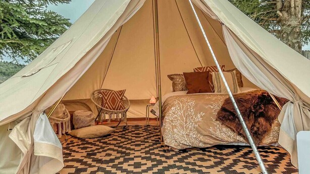 A tent with a bed, a chair, and a patterned rug. - The willow boho tent (Irwin)