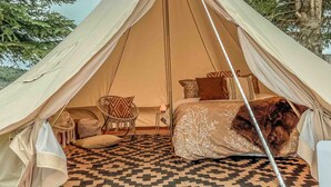 A tent with a bed, a chair, and a patterned rug. - The willow boho tent (Irwin)
