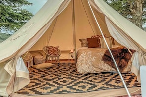 A tent with a bed, a chair, and a patterned rug. - The willow boho tent (Irwin)