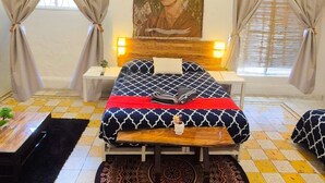 A bedroom with a bed, a round patterned rug, a small table, and a painting on the wall. - Economic Master double Queen-size-room in Downtown Mérida (Mérida)