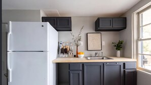 Uma cozinha moderna com armários escuros, uma geladeira branca, uma pia e uma janela que ilumina naturalmente.