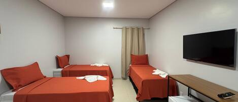 Een hotelkamer met twee bedden, een televisie, een bureau en een koelkast.