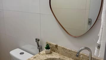 Um banheiro com pia de mármore, vaso sanitário e espelho com moldura de madeira.
