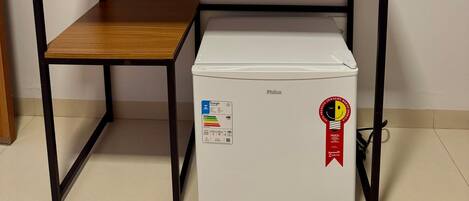 A room with a wooden table and a white refrigerator with a sticker.