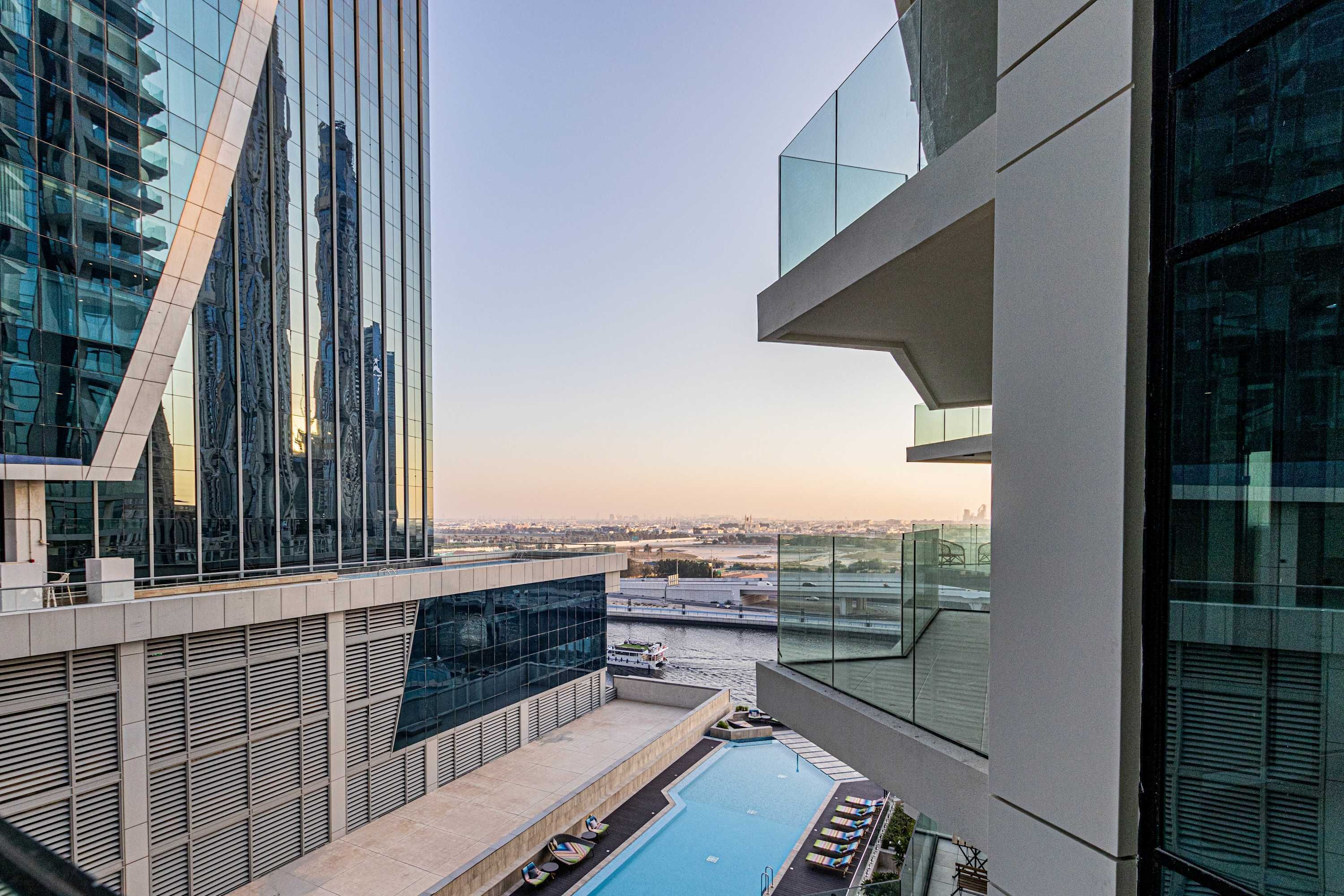 Un edificio moderno con piscina en la azotea, ventanas amplias y vistas a la ciudad.