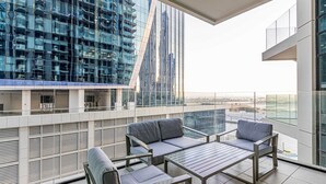 A modern balcony with a glass railing, a sofa, and a table.