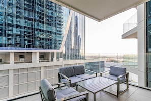Un balcon moderne avec une balustrade en verre, un canapé et une table.