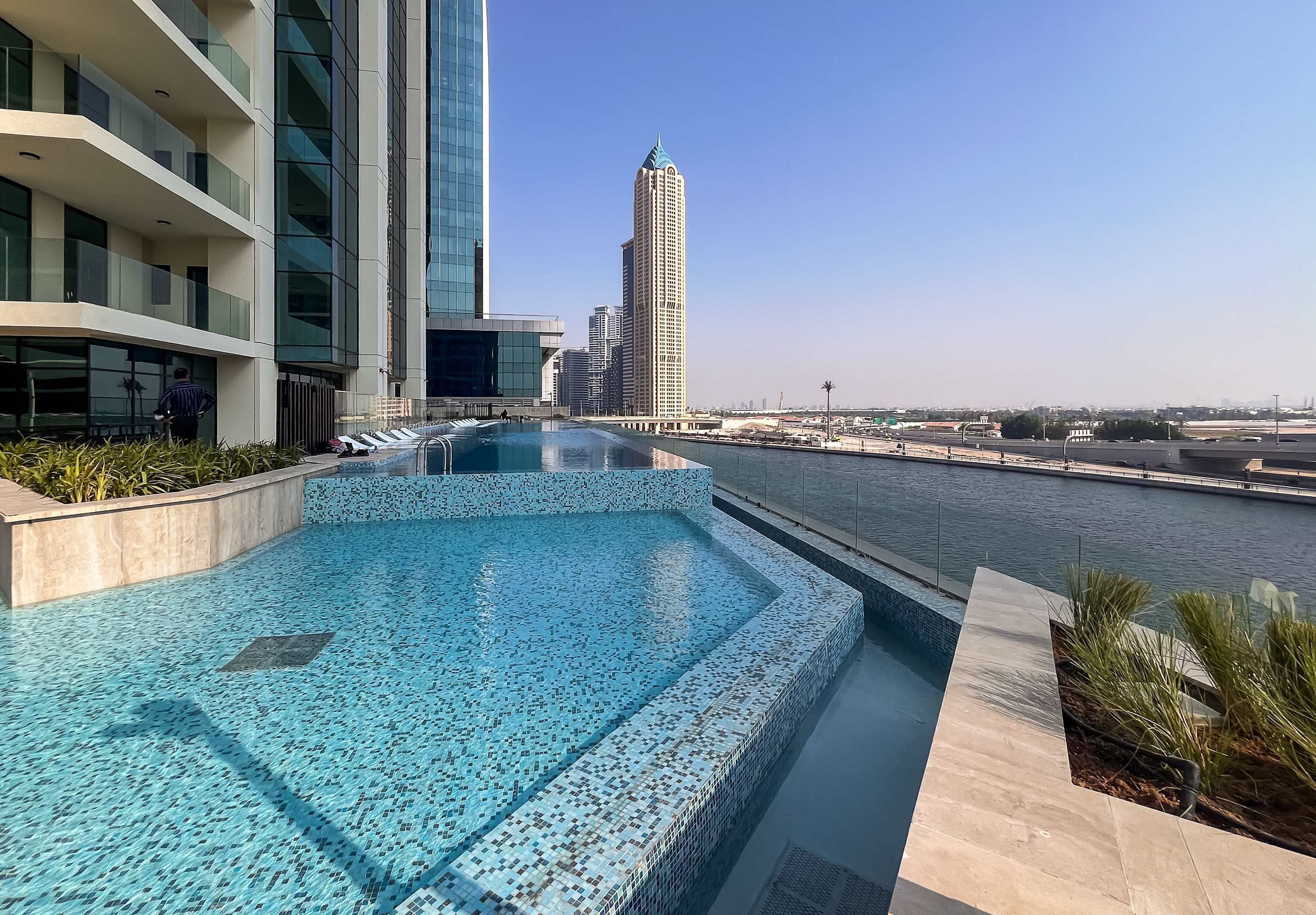 A modern hotel pool with a city view, surrounded by high-rise buildings.
