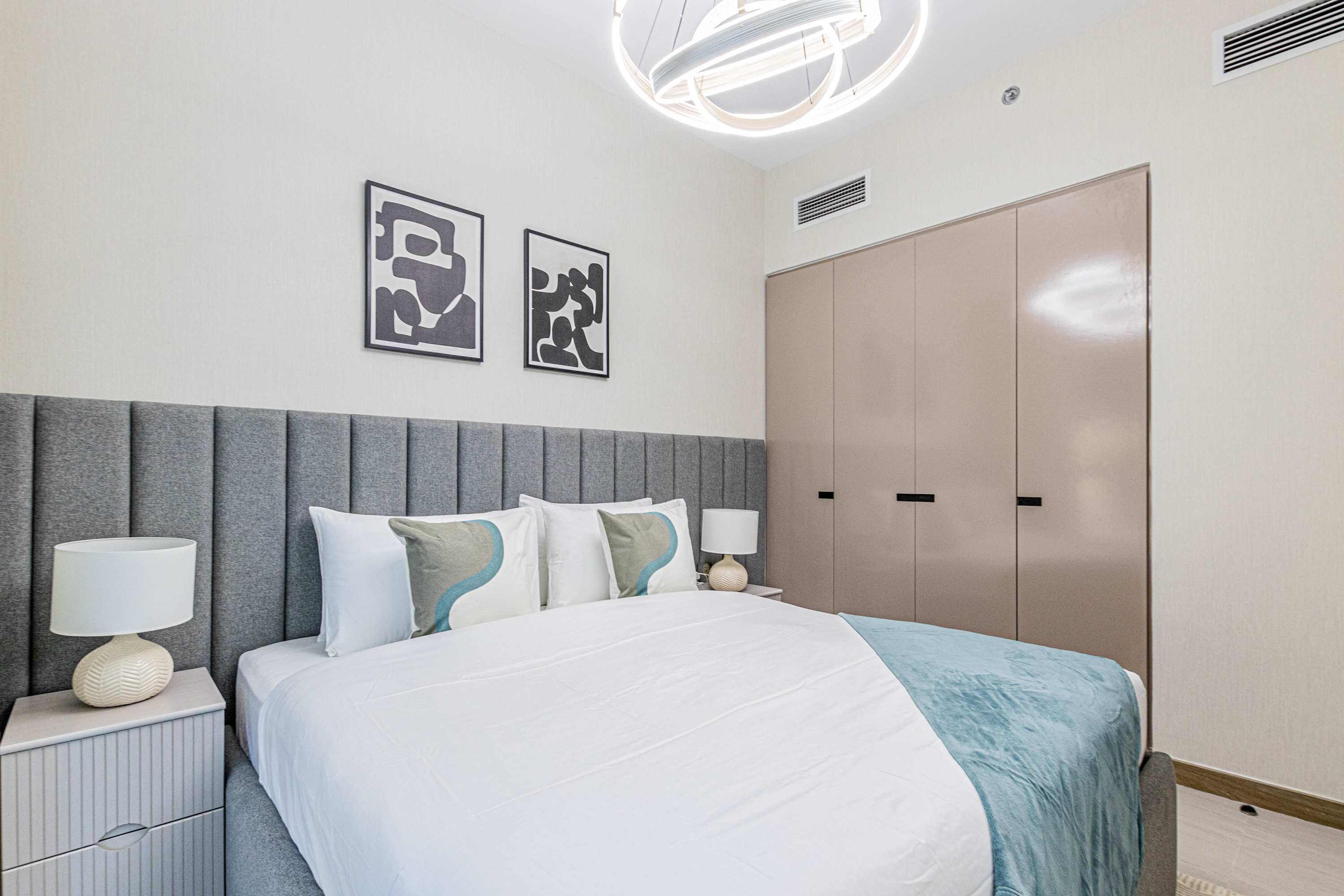 Un dormitorio moderno con cama, mesitas de noche, armario y decoración en la pared.