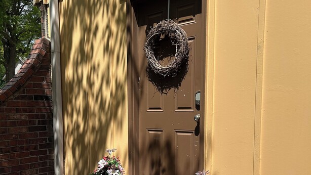 A brown door with a wreath, potted plants, and a brick wall. - Lovely 2-bedroom room rental in Blue Springs (Blue Springs)
