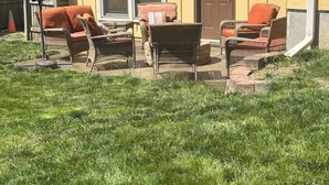 A yellow building with a front door, large windows, and a patio area with wicker furniture and a red umbrella. - Lovely 2-bedroom room rental in Blue Springs (Blue Springs)
