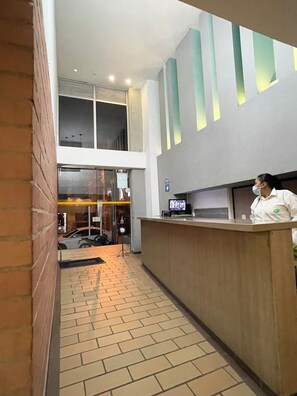 Un área de recepción con mostrador, suelo de baldosas y pared de ladrillo.