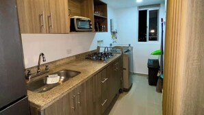 A kitchen with wooden cabinets, a gas stove, a microwave, and a sink.