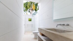 A modern bathroom with a large sink, a toilet, and a small window with a view of palm trees. - Yeguas Z26 by Wynwood House (Anapoima)