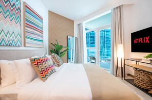A hotel room with a bed, a TV, a large window, and a balcony.