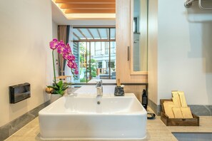 A modern bathroom with a large white bathtub, a wooden side table with toiletries, and a potted orchid. - A.z.sunrise Resort And Fitness Club (Choeng Thale)
