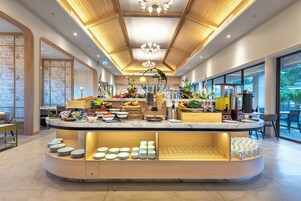 Una barra de desayuno moderna con diversas frutas, bebidas y platos.