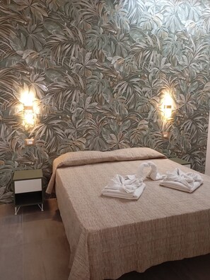 A neatly made bed with a beige bedspread, two wall-mounted lights, and a nightstand with a small drawer. - Tourist Location Le Vele I Relax with the whole family in this accommodation (San Pietro In Bevagna)