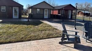 A building with a red exterior and a brown roof, a small porch, and a paved walkway. - Cabin 1 in peaceful Reed Point 3 minutes from Yellowstone River (Reed Point)