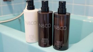 Three N&CO shampoo bottles on a bathroom counter.