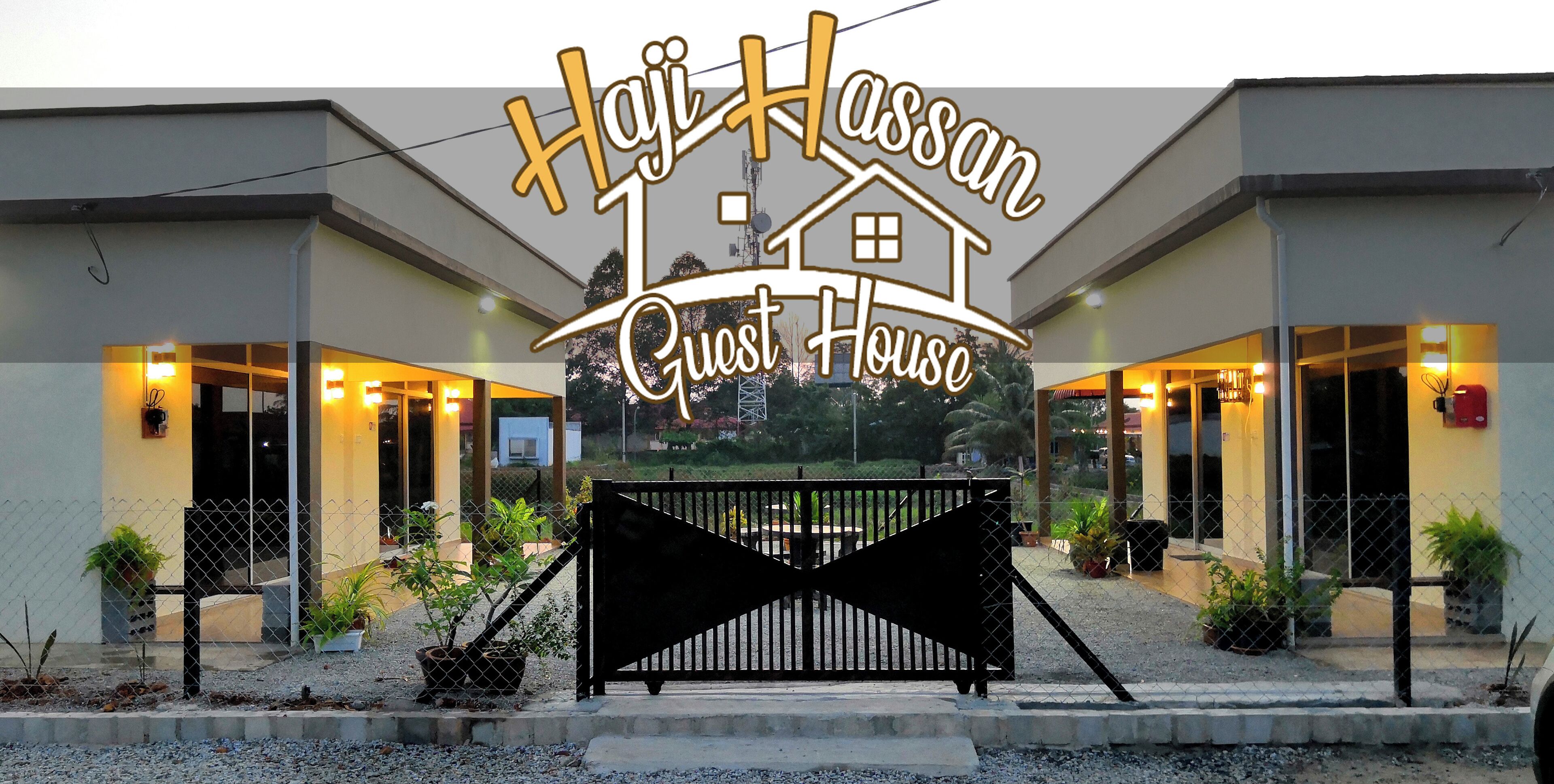 Una casa de huéspedes con un letrero que dice "Haji Hassan Guest House" y un portón negro al frente.