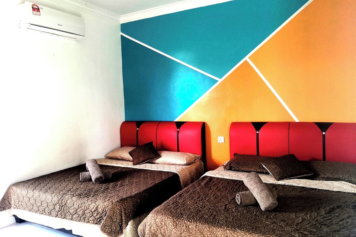 Habitación con dos camas, cada una con cubrecama y almohadas de textura marrón, y cabecera roja.