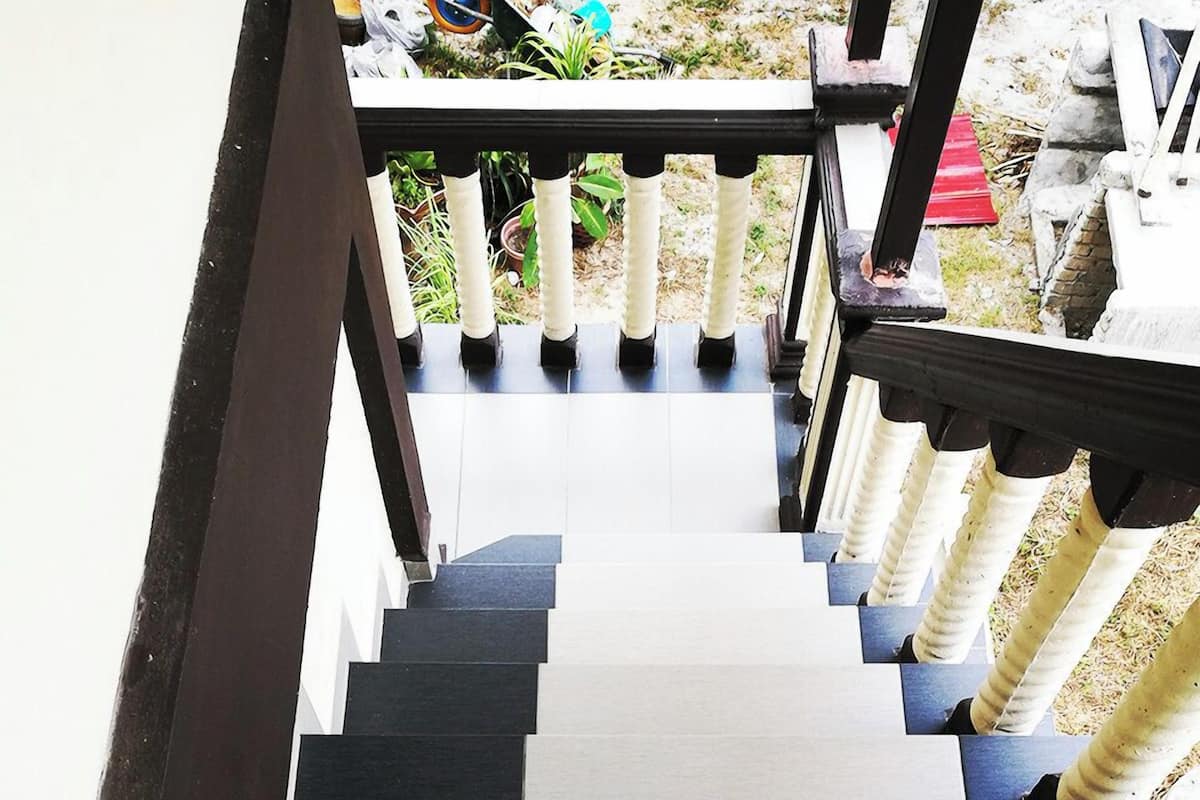 Eine Treppe mit abwechselnd schwarzen und weißen Stufen, die zu einem Balkon mit Geländer führt.