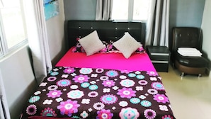 A bedroom with a bed, two pillows, a nightstand, a chair, and a window with curtains. - Haji Hassan Guest House (Langkawi)