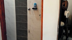 Et badeværelse med bruser, toilet og håndvask.