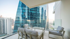 A modern living room with a glass wall, a sofa, a chair, and a small table.