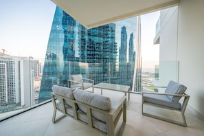 A modern living room with a glass wall, a sofa, a chair, and a small table.