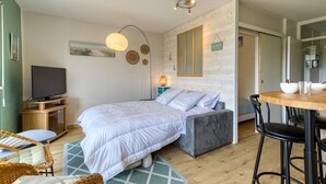 A bedroom with a bed, bedside table, lamp, and a TV. - Bel Appartement Proche Mer (Royan)