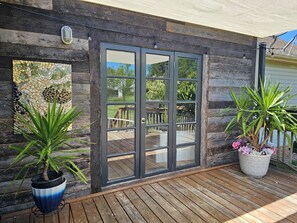 Une terrasse en bois avec une porte vitrée donnant sur un patio extérieur.
