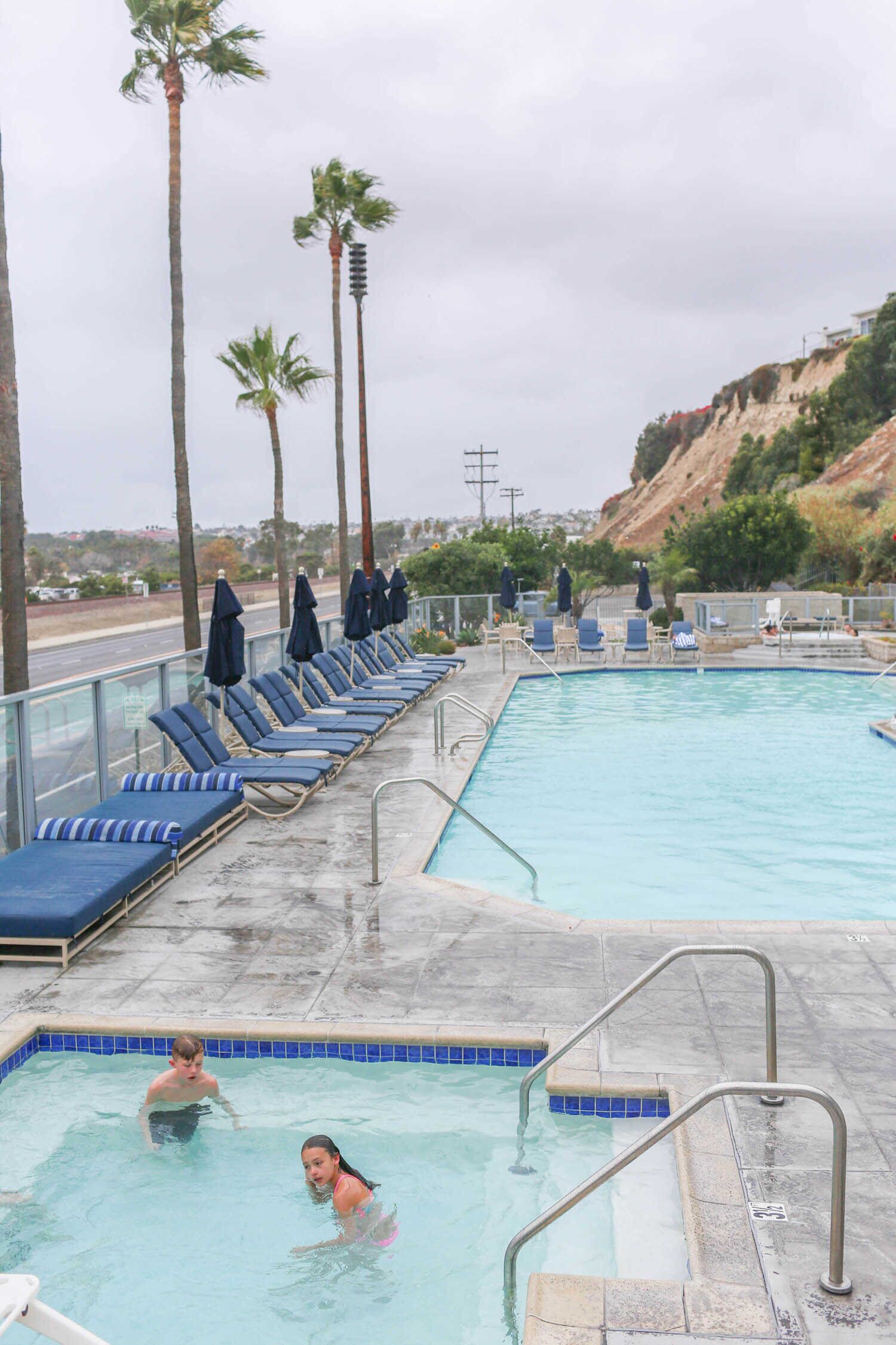 A swimming pool with lounge chairs and palm trees.