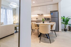 A modern kitchen with a dining area, a sofa, and a potted plant.
