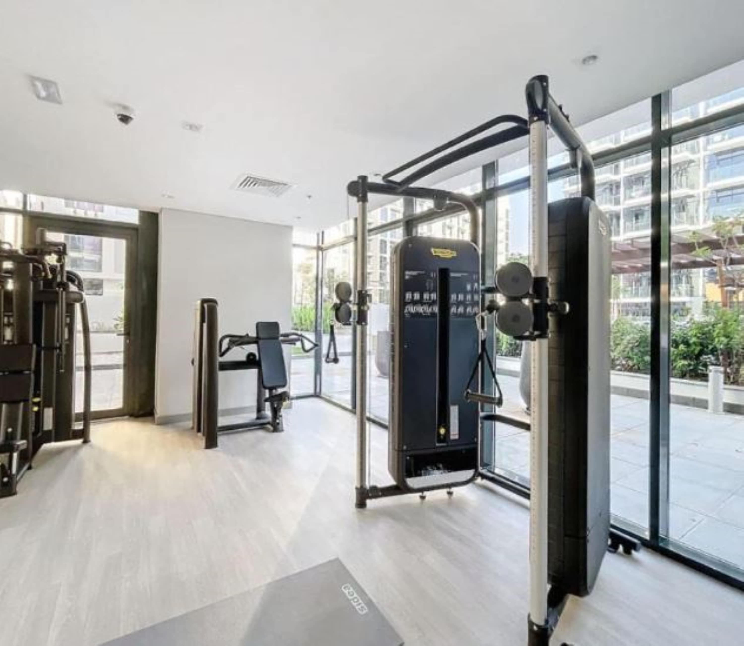 A modern gym with various exercise equipment, large windows, and a clean, minimalist design.