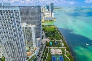 Un hotel moderno con vistas al océano y un parque con canchas de tenis.