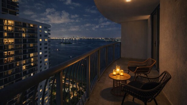 A balcony with a view of a cityscape and a body of water at dusk.