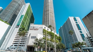A modern urban skyline with high-rise buildings, including a prominent cylindrical tower and a building with a curved facade.
