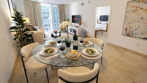 A dining area with a round glass table, four chairs, and a white cabinet in the background.