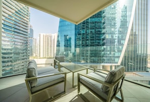 A modern balcony with glass walls, a sofa, a table, and a chair.